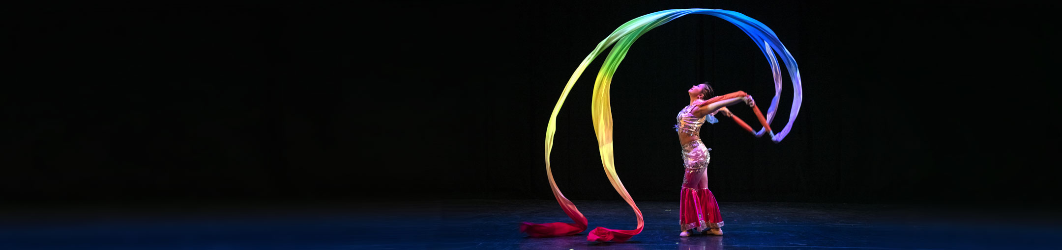 A woman dances on stage with colorful ribbons.