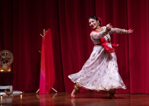 A woman dances in front of a red curtain.