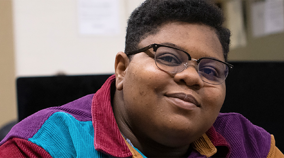 Student sitting next to a computer screen.