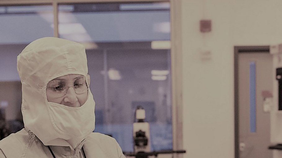 people in a clean room, wearing protective suits.