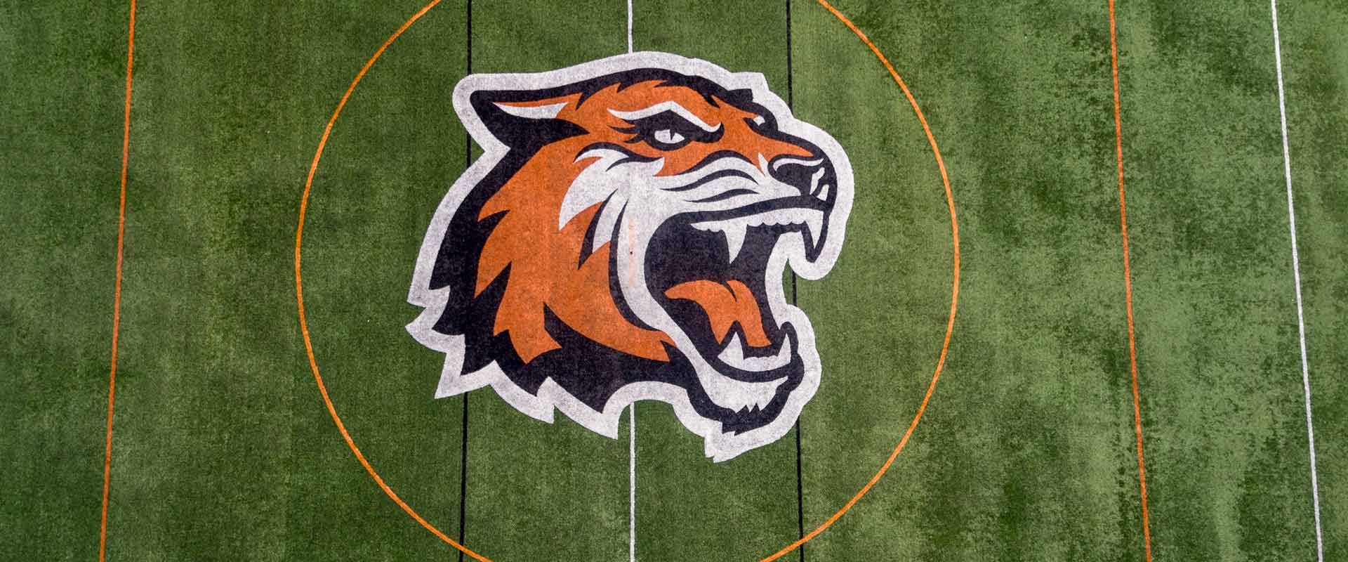 Overhead view of R I T tigers athletics logo on a turf field.