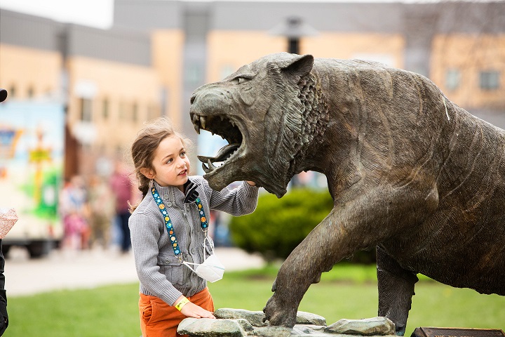 A child posing with Ritchie the Tiger