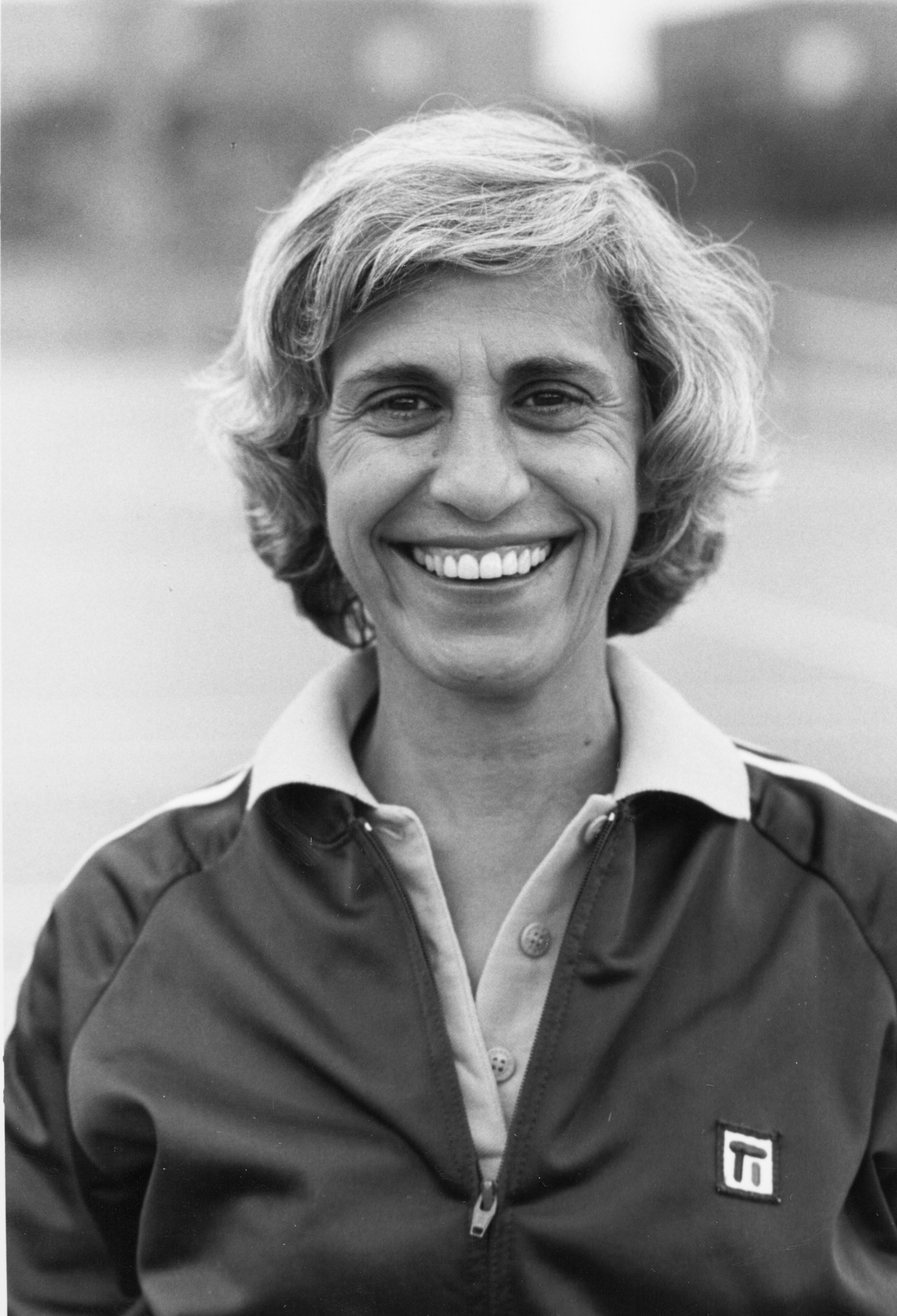 Black and White photo of Anna Nealon In a track jacket standing outside with a smile