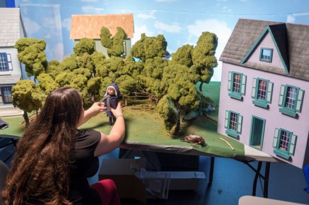 Student placing stop-motion animation figure on set