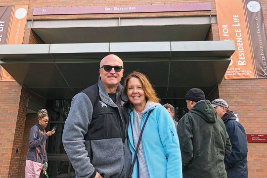 A couple stands outside the residence hall where they met.