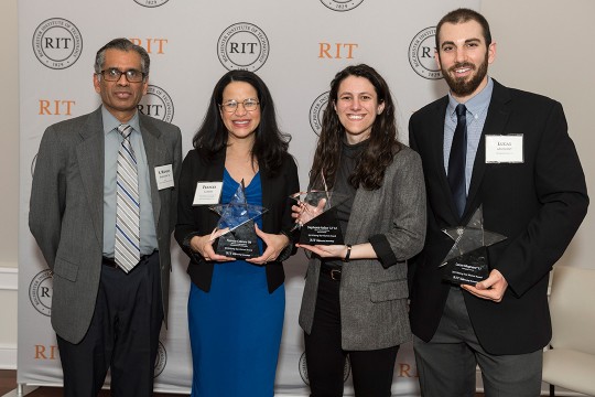 Four men and women stand holding star-shaped glass awards.