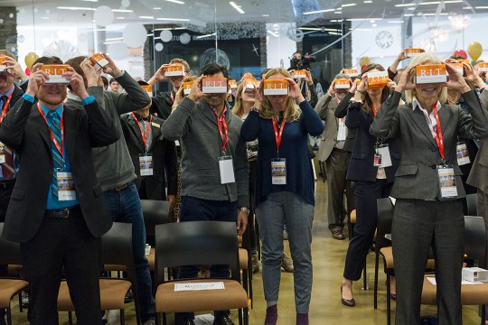 Crowd of people stands looking at Google Cardboard virtual reality viewer