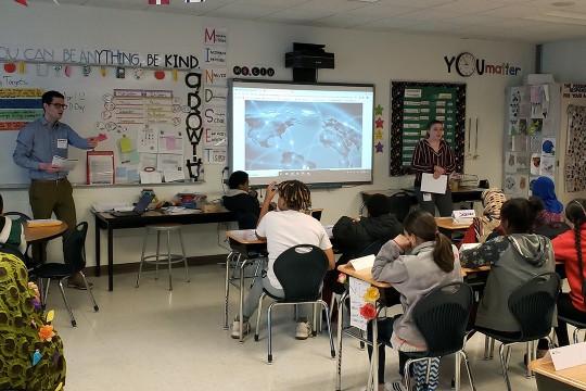 Man stands in front of class of elementary school children.