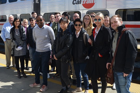 Group of students stands on train platform.