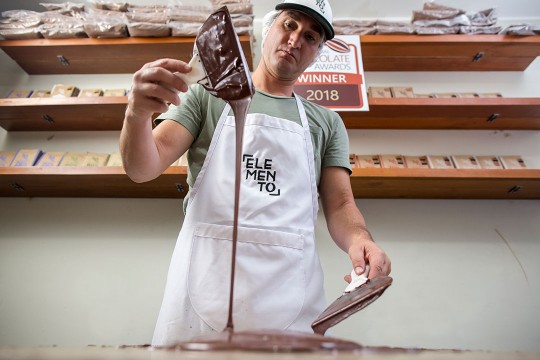 Chocolate-maker drips chocolate off of spatula.