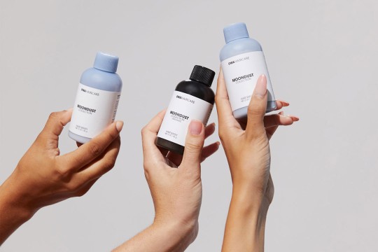 Hands holding hair-care products.