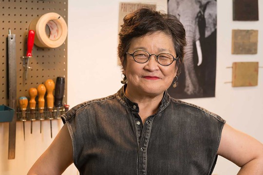 artist Wendy Maruyama posing in a studio with woodworking tools.