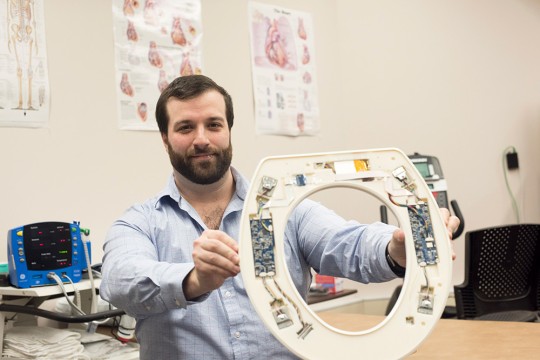 researcher holding up a toilet seat showing sensors on the underside.