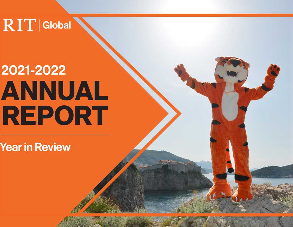 RIT tiger mascot poses on a sunny cliffside, framed by orange geometric Annual Report design elements.