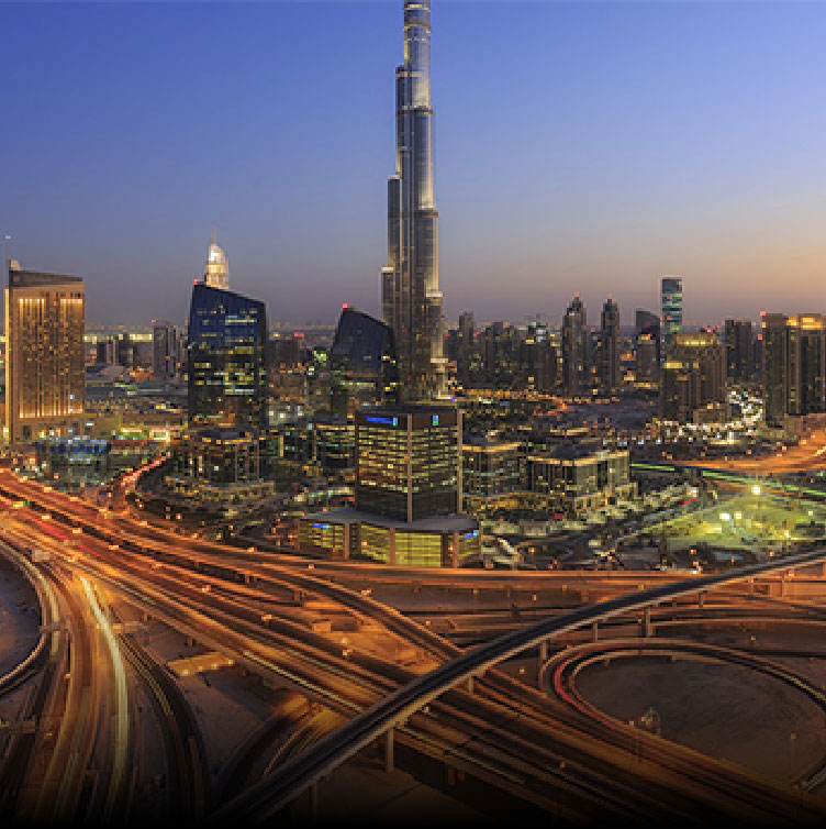 A stunning cityscape of Dubai at dusk, featuring the Burj Khalifa surrounded by illuminated skyscrapers and intricate highway intersections.