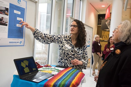 A person pointing to a poster with an audience.