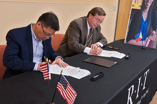 Two men at a table signing papers.