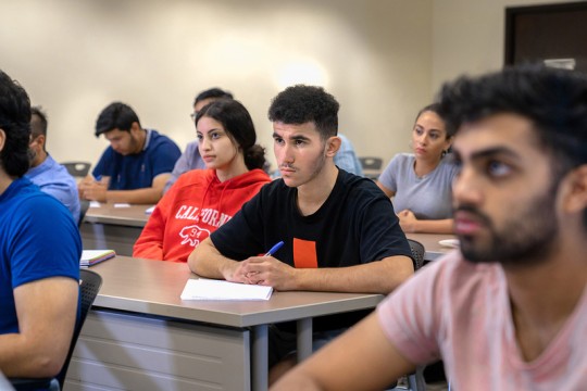 Students sit at desks in classroom.