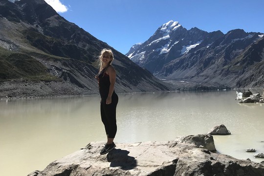 woman standing on rock near mountains.