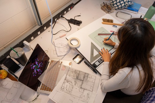 overhead view of woman working on architectural designs.