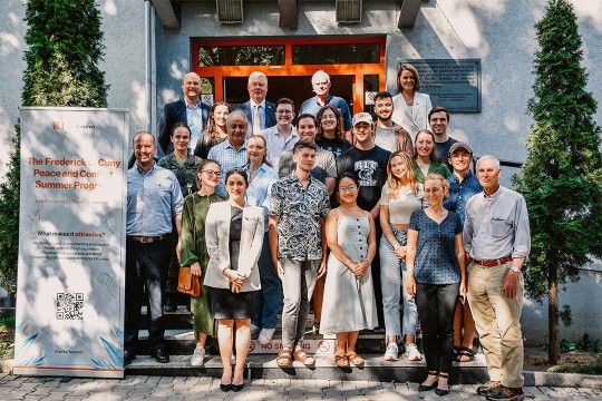 group of students and faculty members standing outside on steps to a building.