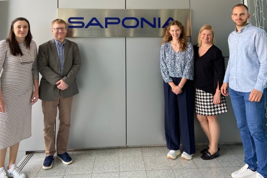 Five business-dressed people stand in front of sign that reads Saponia.