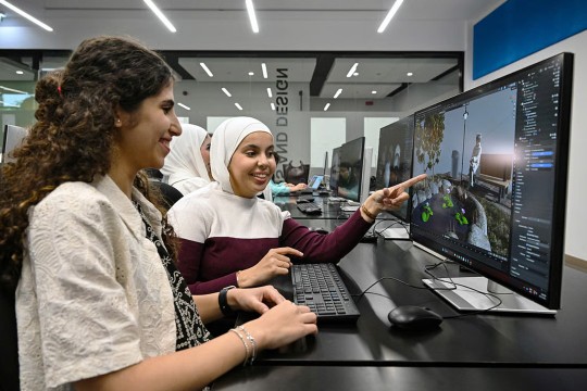Two students at R I T Dubai work together at a computer in a computer lab.