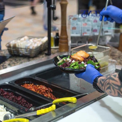 Over the shoulder shot serving a salad to a customer