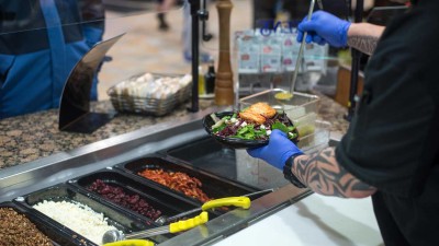 Over the shoulder shot serving a salad to a customer