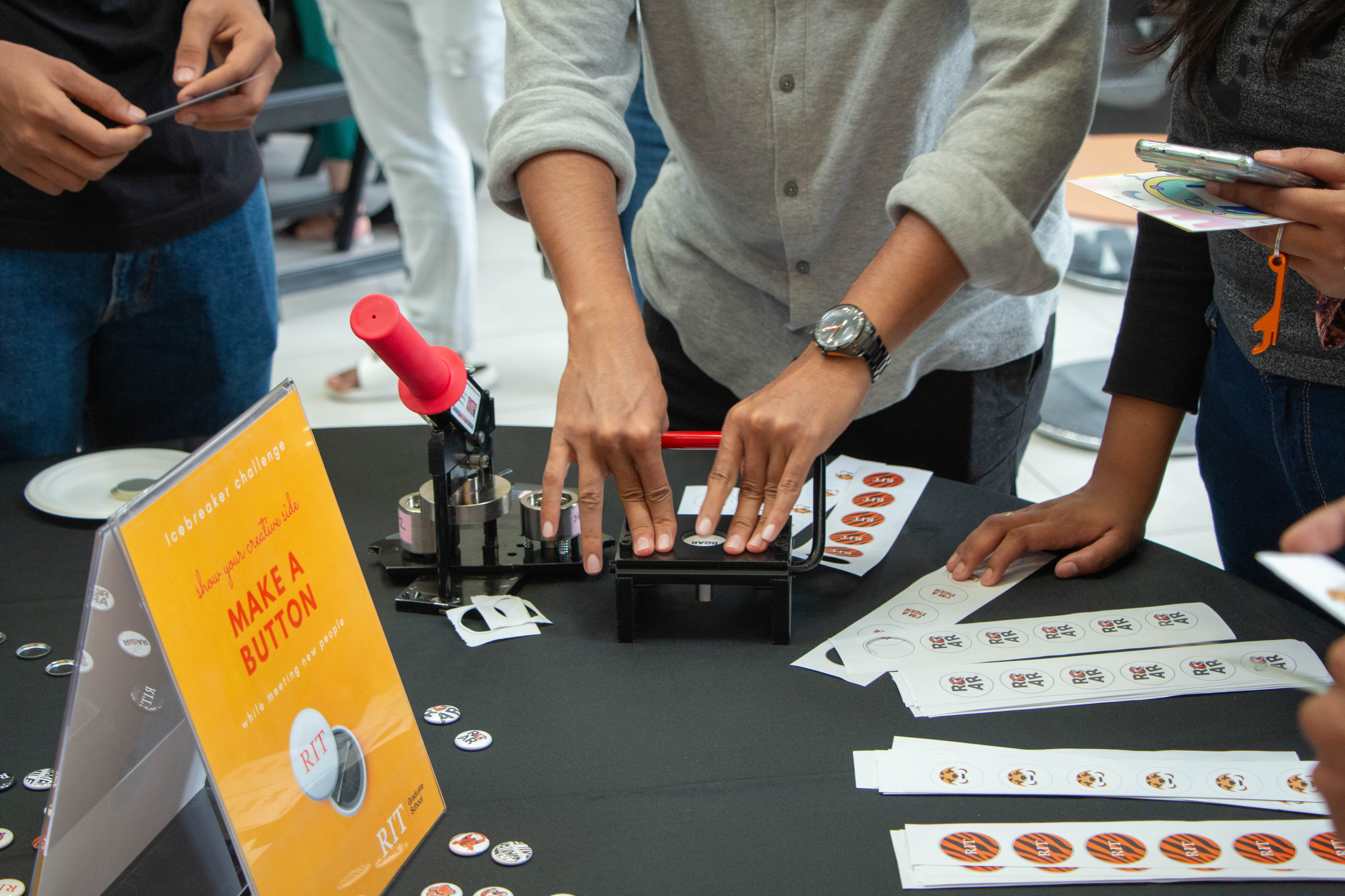 make a button table with a student making a button with the RIT tiger on it