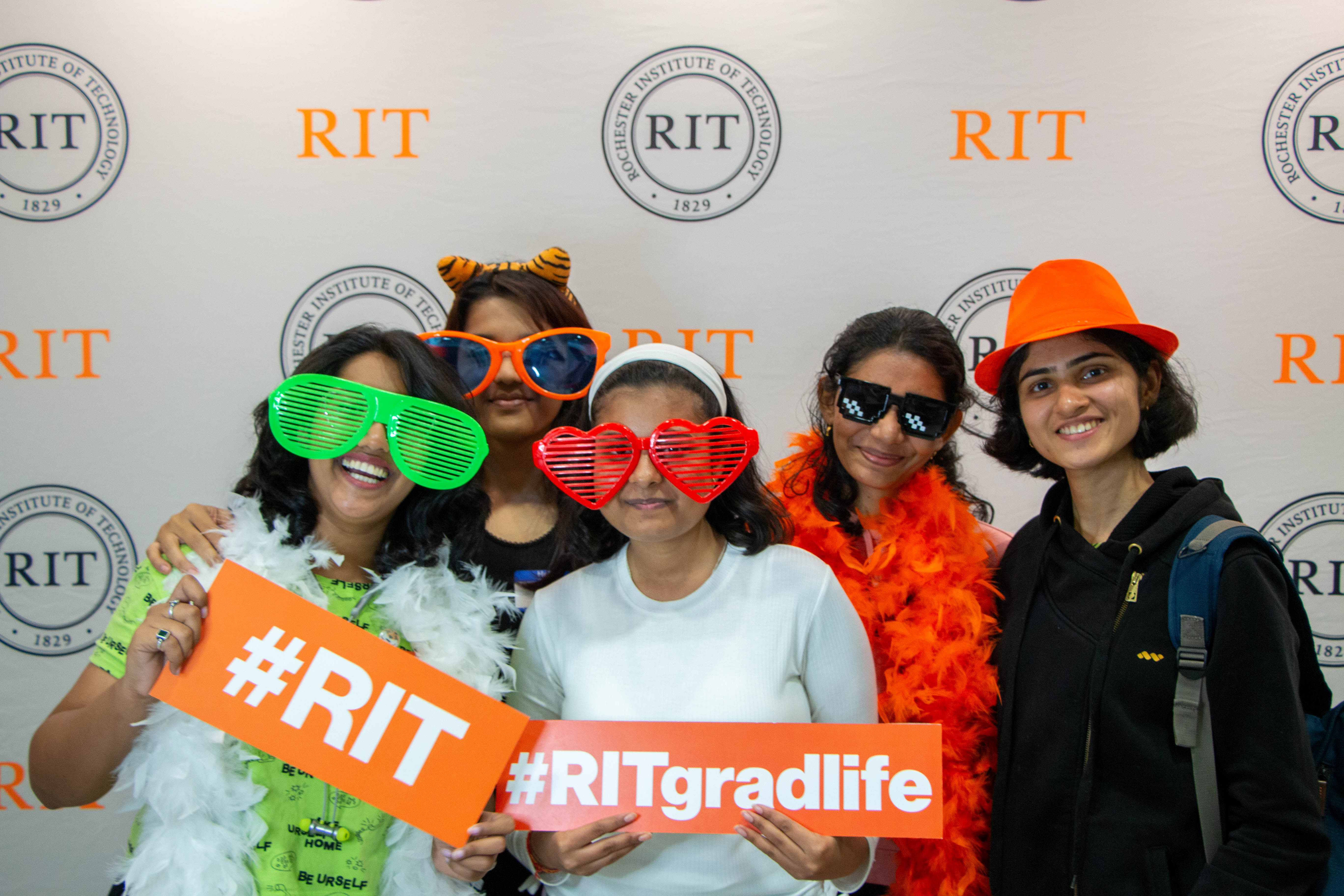 group of 5 students in the photobooth with #ritgradlife prop