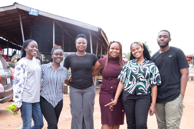 a group of 6 people stand in a village in a remote area.