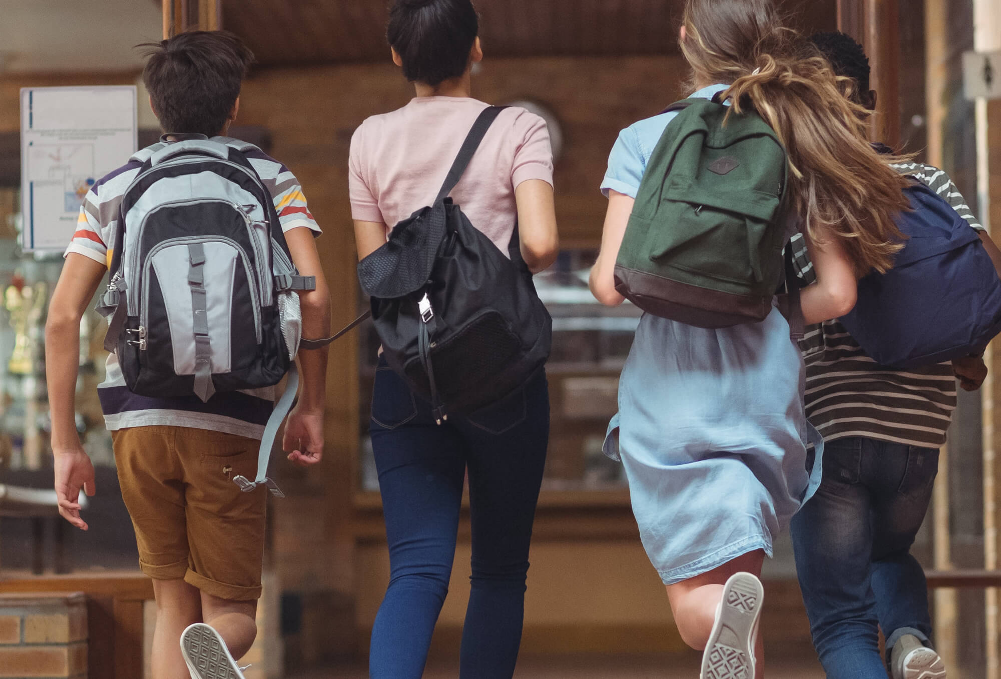 children running into a school building with backpacks on