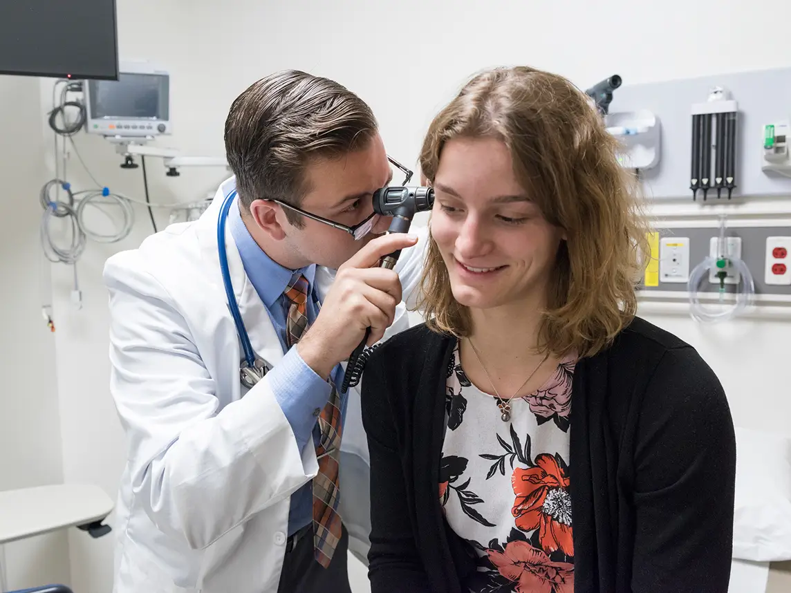 A professor demonstrates how to examine a patient's ear.