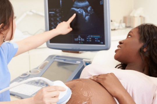 Sonographer takes images of pregnant woman's belly.