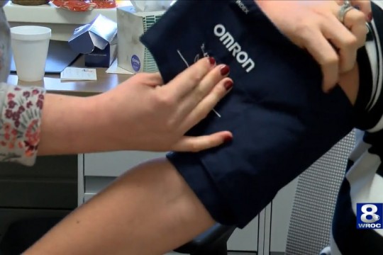 Nurse putting blood pressure cuff on patient's arm.