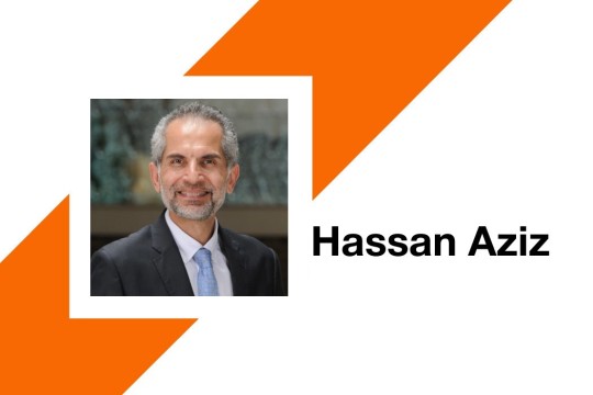 a man with gray hair and beard sits for a headshot with a gray jacket and white buttons down shirt. An orange stripe appears behind his photo and the name Hassan Aziz appears to the right.