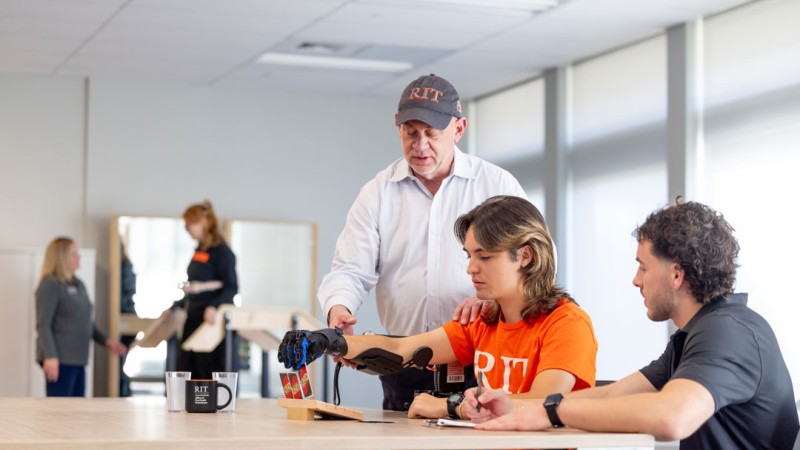 Access to emerging technologies gives RIT occupational therapy doctoral students like Joshua Luciano, right, new ways to apply design interventions that support movement and independence. Stephen Van Lew, left, assistant professor, demonstrates how to use a rehabilitation glove.