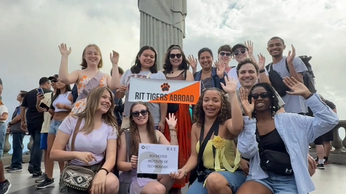 Honors Students in Brazil Posing for a group picture with a sign that says RIT Abroad