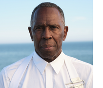 Charles Gaines in a white button up shirt with a blurry background of the sea and the sky