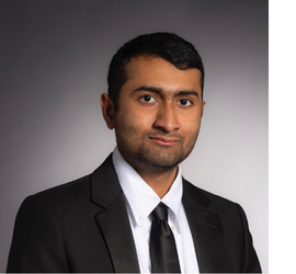 Srikar headshot on grey backgroud. Srikar is wearing a tie and black sportcoat.