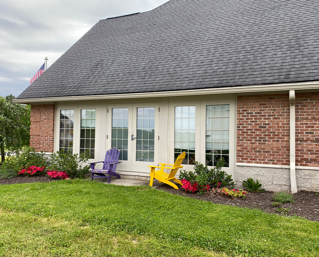 exterior of Greek Circle brick residence with Adirondack chairs outside