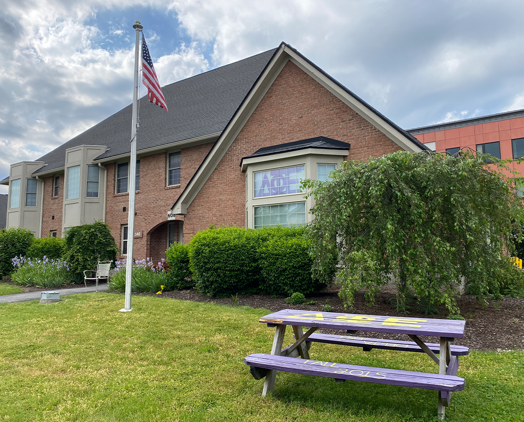 exterior of Greek Circle brick residence with a flag pole and picnic table outside