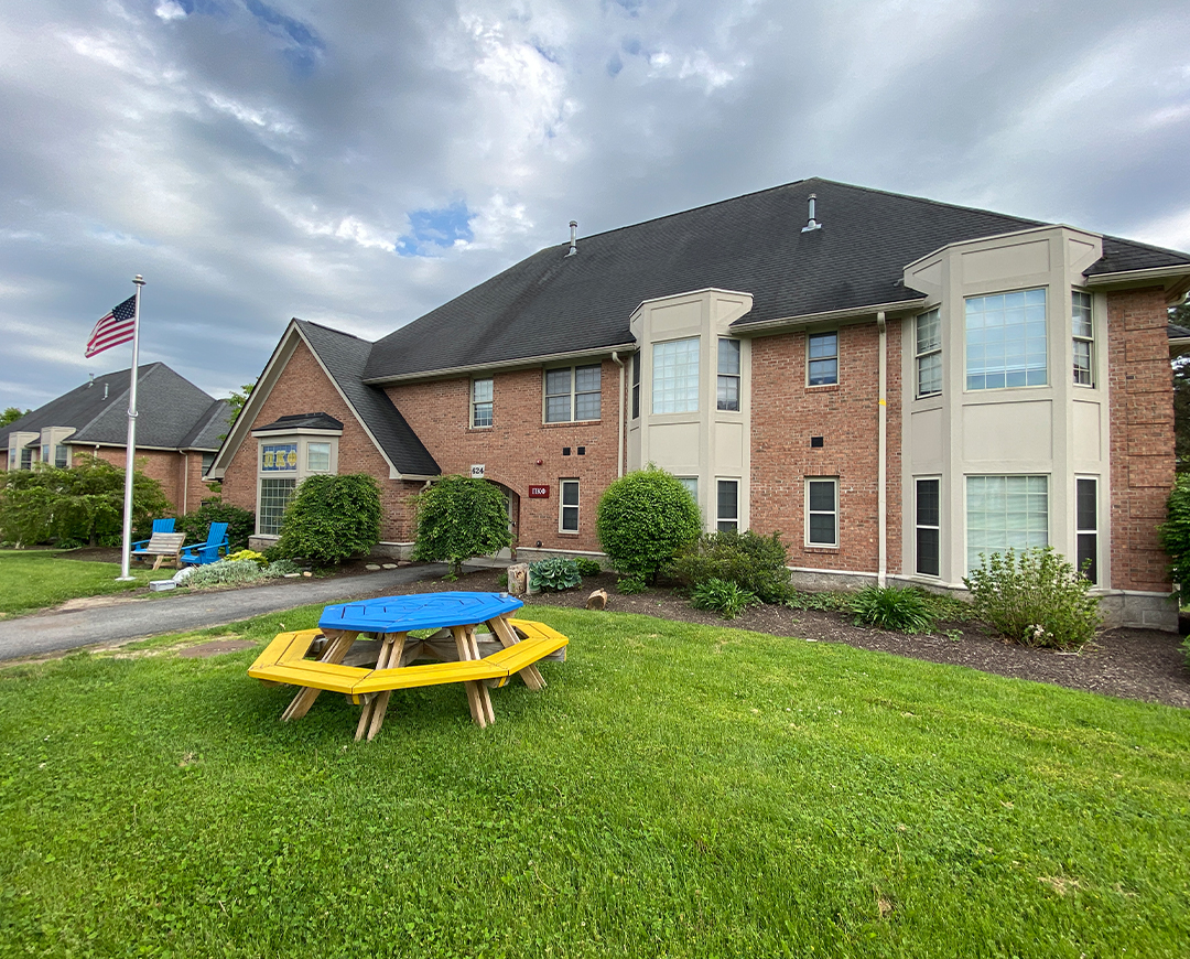 exterior of Greek Circle brick residence with a flag pole and round picnic table outside