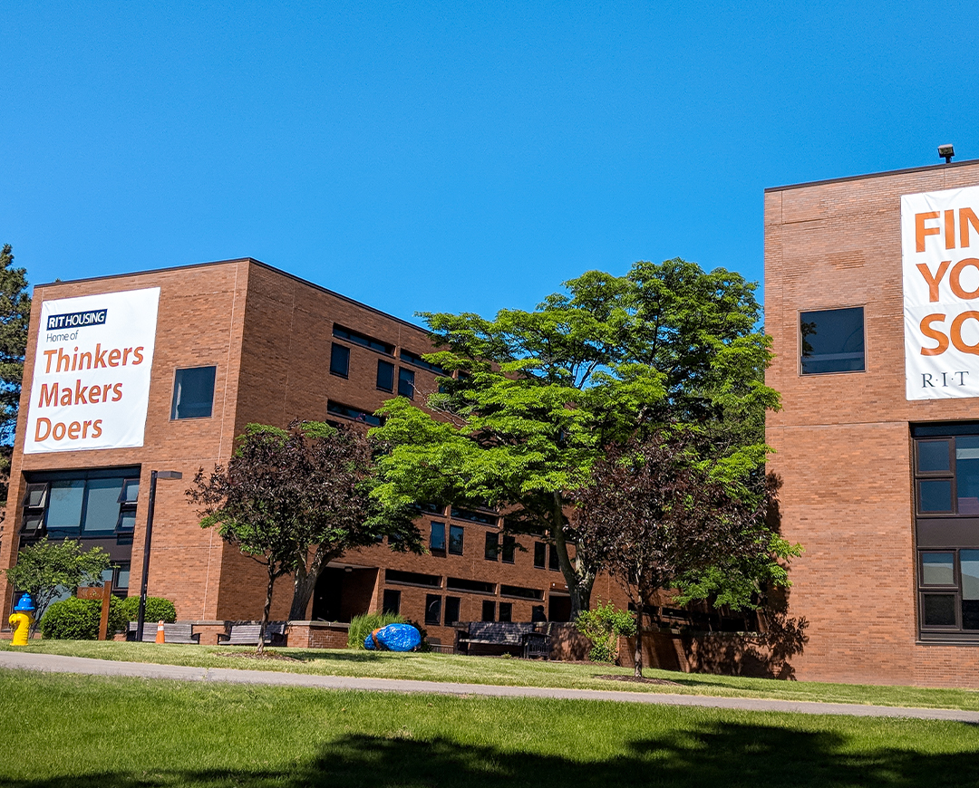 residence halls a and b with banners on them reading "Home of Thinkers, Makers, Doers" and "Find Your Squad"