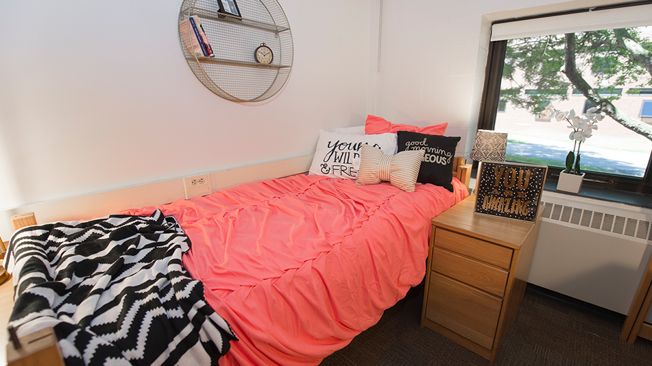 pink comforter on a bed in front of a window