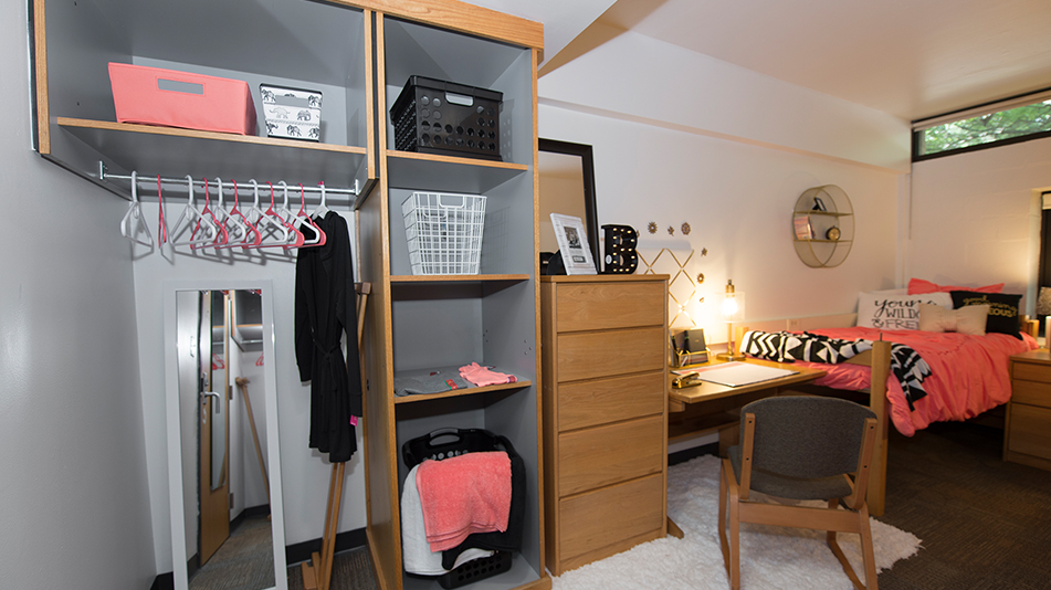 residence hall room showing a closet, shelves, desk, and bed