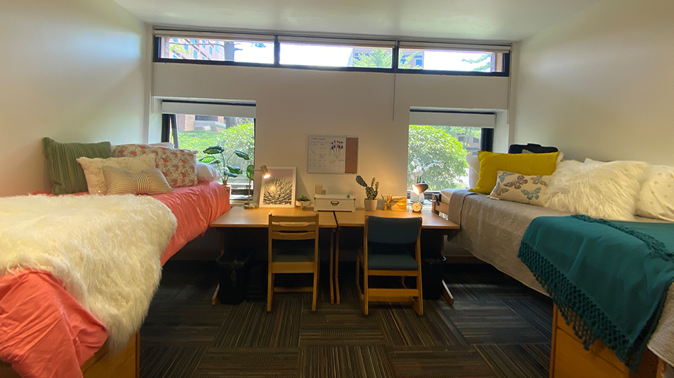 two beds and two desks in a residence hall room