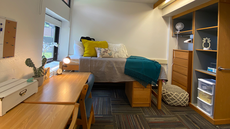 twin bed with a blue comforter, desk, and closet system