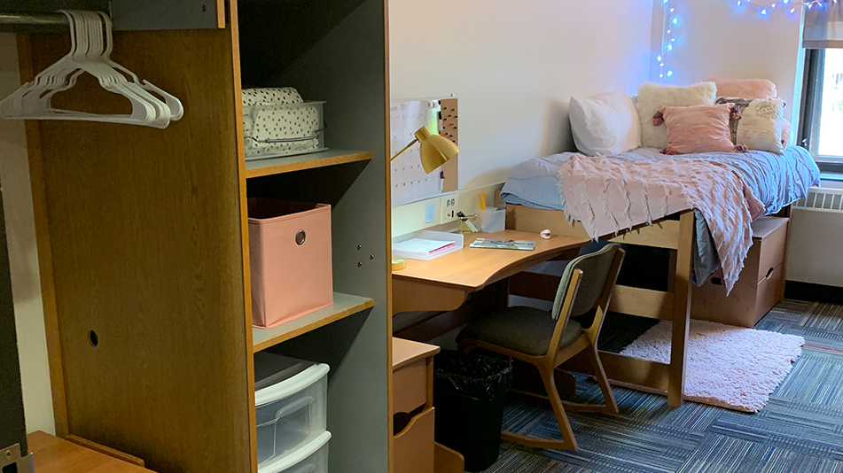 twin bed with a comforter, desk, cubbies, and closet